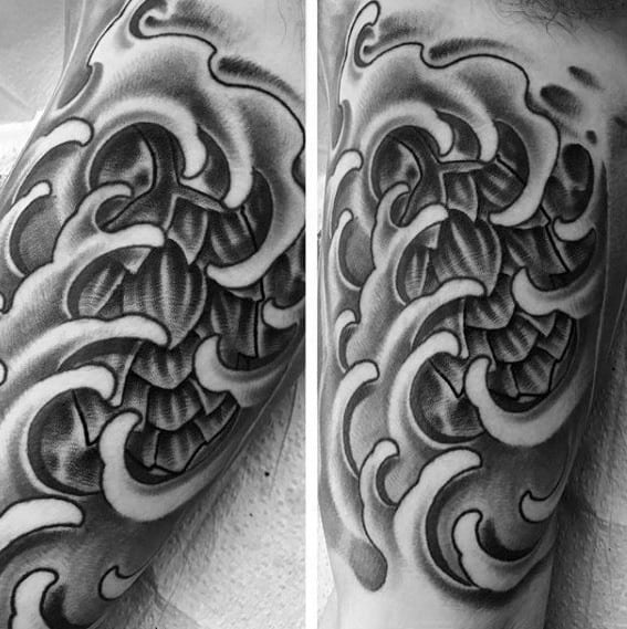 Black and gray tattoo featuring a stylized hop cone surrounded by flowing waves or smoke-like patterns, blending botanical and abstract elements with smooth shading.