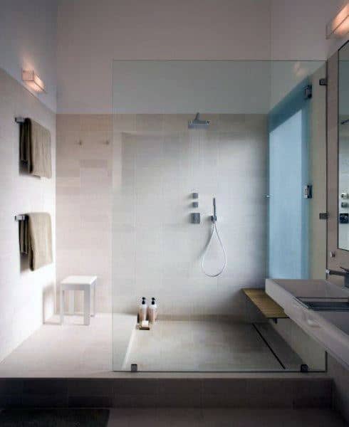 Minimalist bathroom with a sleek shower, modern fixtures, beige tiles, and towels hanging on the left wall