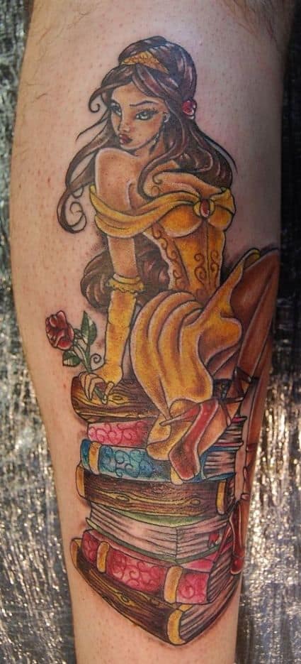 Tattoo of Belle in a detailed, artistic style, sitting atop a stack of colorful books with a rose beside her, featuring rich shading.