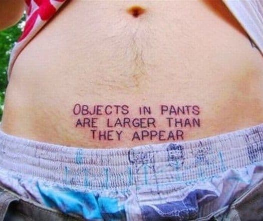 Funny tattoo on the lower abdomen reading 'Objects in pants are larger than they appear,' mimicking a classic side mirror warning.