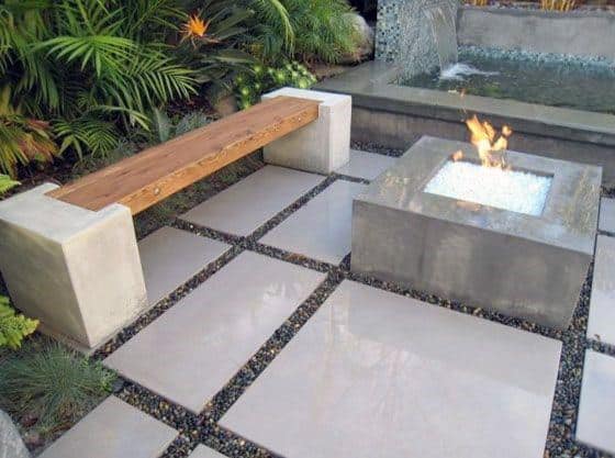 Modern patio with concrete fire pit, sleek wooden bench, and geometric stone pavers.