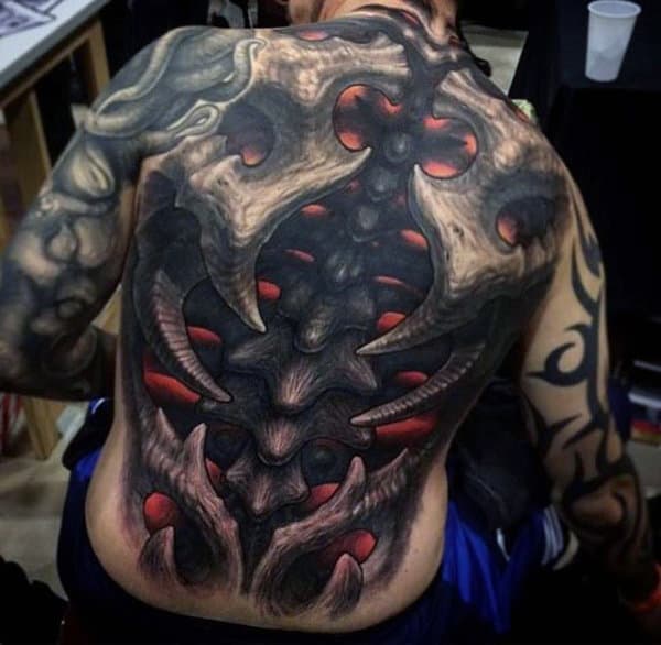Person showing a large, intricate, biomechanical-themed tattoo covering their back