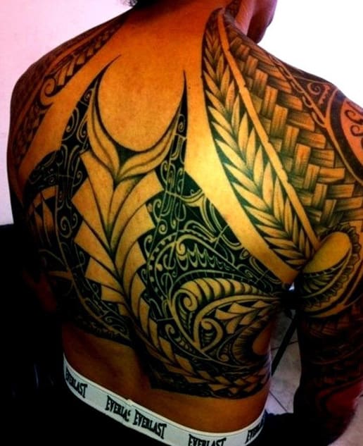 Person with an intricate black tribal tattoo design covering their entire back