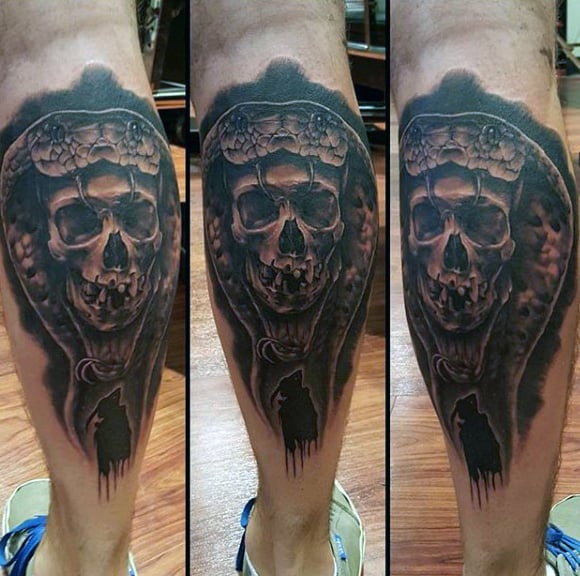 Dark, detailed calf tattoo of a skull with a snake coiled around it, featuring deep shading and a silhouette of a howling wolf
