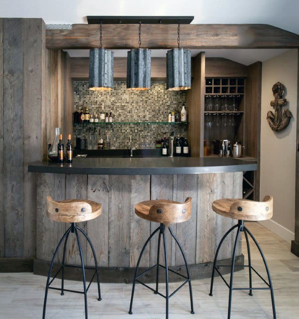 Rustic home bar with wooden stools, mosaic backsplash, and overhead industrial bar pendant lights
