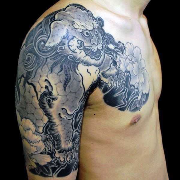 Upper body tattoo of a detailed lion with floral elements on a person's shoulder and chest