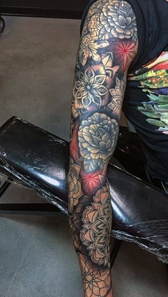 Arm covered in intricate flower tattoo sleeves in vivid colors and detailed patterns