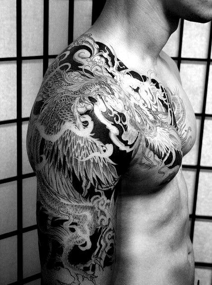 Black and white image of a man with a detailed tattoo of a phoenix on his shoulder