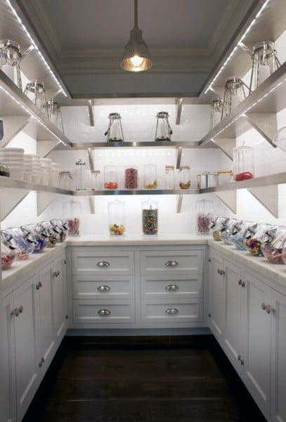 Spacious pantry with white cabinets, glass jars, and under-shelf lighting.