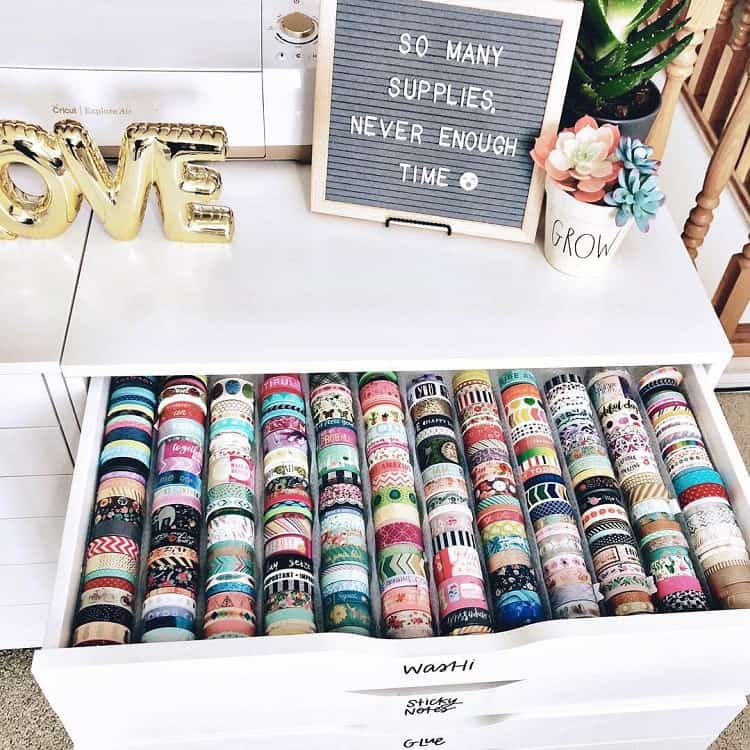 Drawer filled with colorful washi tapes, a sewing machine, decorative items, and a letter board message