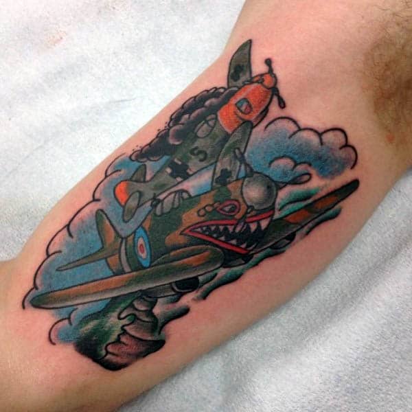 Tattoo of two airplanes in mid-air with clouds in the background on a person's arm