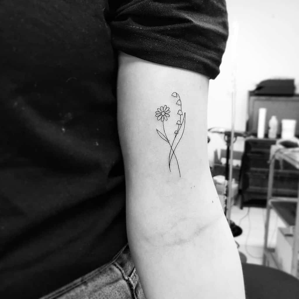 Minimalist fine-line tattoo of a daisy and Lily of the Valley, featuring delicate, simple floral outlines