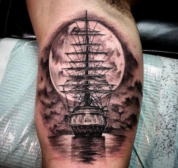 Black and grey tattoo of a detailed sailing ship under a full moon, reflecting on water with dramatic shading and a dark sky