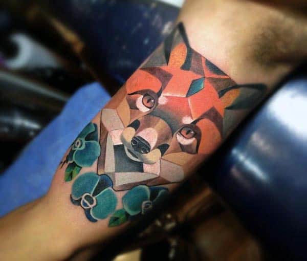 Geometric wolf tattoo in vibrant colors with blue flowers, featuring sharp angles and shading for a bold, modern design on the bicep