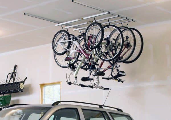 Garage with multiple bikes hanging from a ceiling-mounted storage rack above a car.