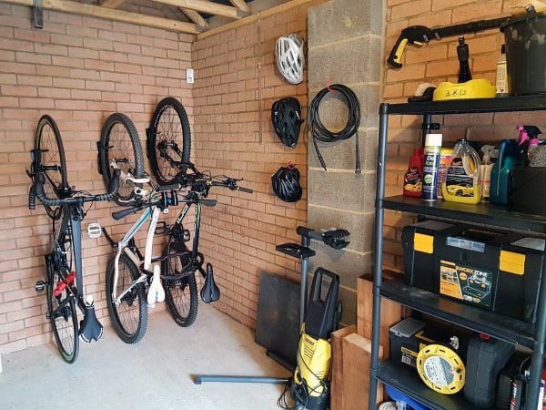 Garage with two bikes mounted on wall racks, tools, and organized storage shelves.