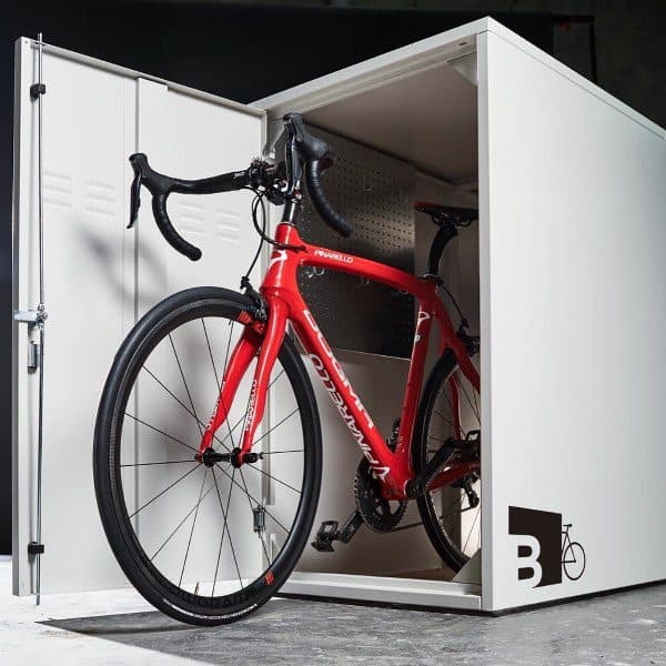 Red road bike stored inside a secure white bike storage locker.
