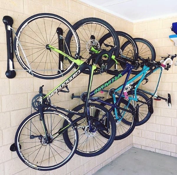 Garage with brick walls, concrete floor, and three bikes mounted on vertical wall racks.