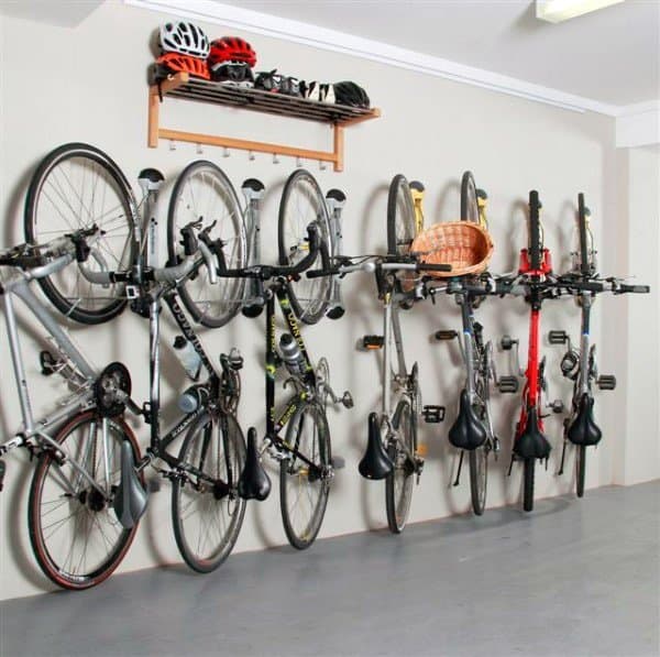 Garage with multiple bikes mounted on vertical wall racks and a shelf for helmets and gear.