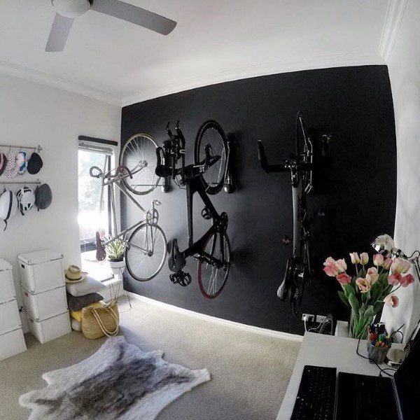 Room with black accent wall featuring three bikes mounted vertically for space-saving storage.