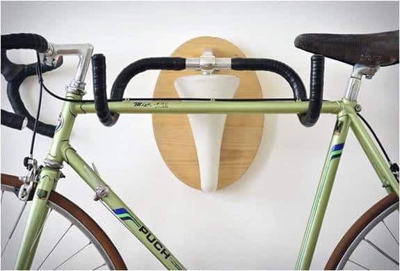 Wall-mounted wooden rack shaped like a minimalist deer antler, holding a green vintage bike