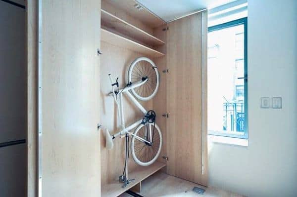 A sleek wooden cabinet with interior shelving, discreetly housing a white bicycle for space-efficient storage.