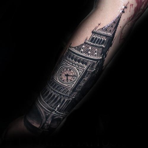 Detailed black and grey tattoo of Big Ben with a dramatic, shadowy effect, highlighting the clock face and intricate architectural details on the forearm.