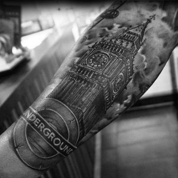 Detailed black and grey tattoo of Big Ben with the London Underground logo beneath, surrounded by dramatic cloud shading.