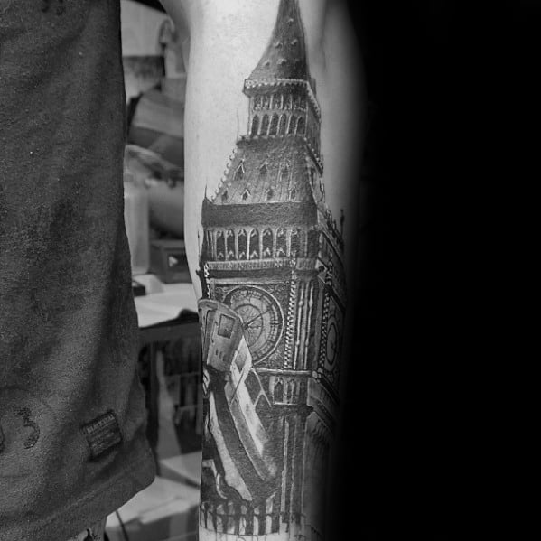 Detailed black and grey tattoo of Big Ben on the forearm, with dramatic shading and architectural details, creating a striking visual impact.