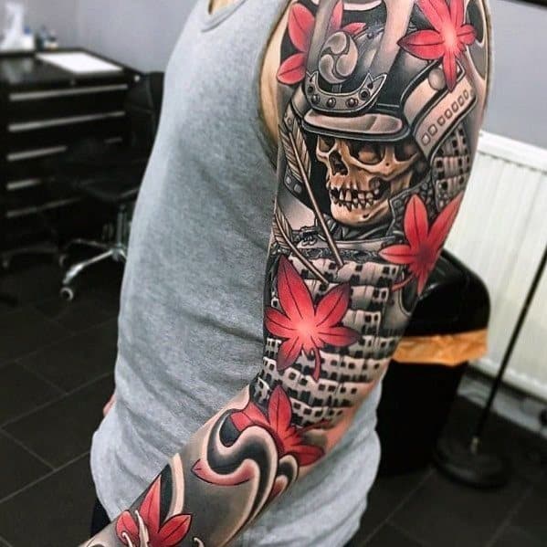 Full-sleeve tattoo featuring a samurai skull, Japanese castle, bold red maple leaves, and intricate shading for a striking warrior-themed design.