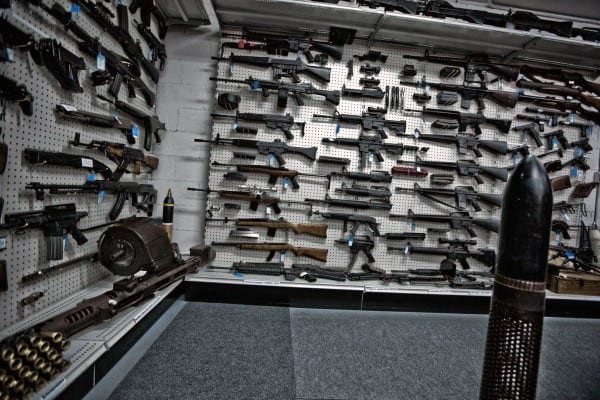 Gun room with extensive wall-mounted firearm collection and large ammunition displays.