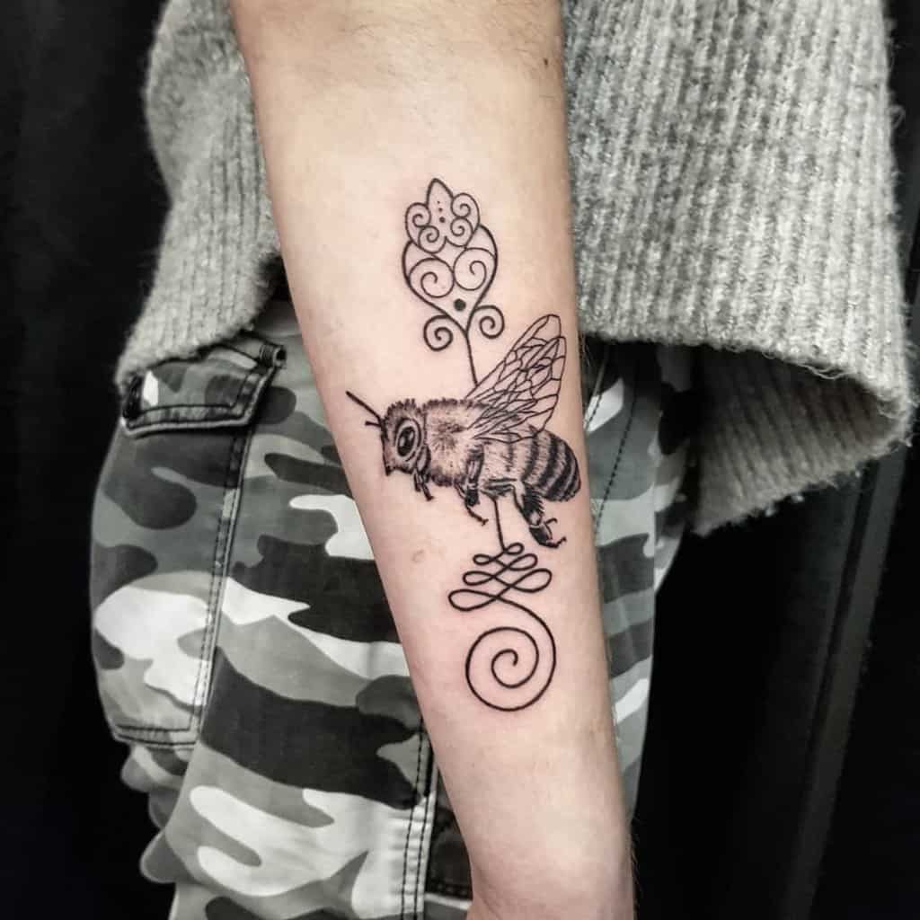 Unalome tattoo with a detailed bee on the forearm, symbolizing hard work, perseverance, and the journey to spiritual enlightenment.