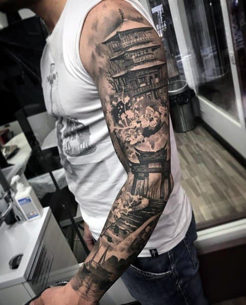 Black and grey full-sleeve tattoo featuring a detailed Japanese pagoda, cherry blossoms, and traditional architectural elements.