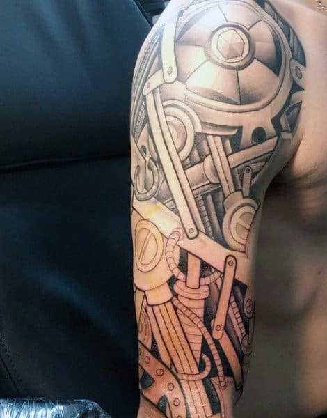 Arm adorned with black and grey tattoo of mechanical gears and machinery