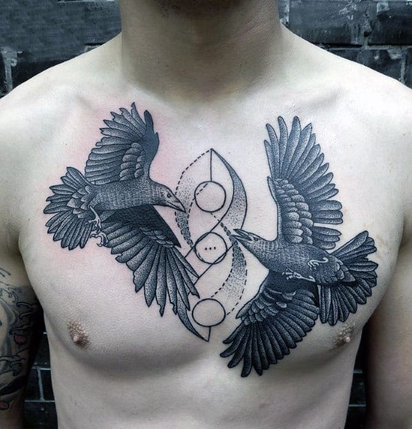 Chest tattoo of two black birds and geometric symbols on a shirtless person's chest