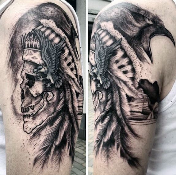 Tattoo of a skull wearing a headdress with feathers and an eagle on a person's upper arm
