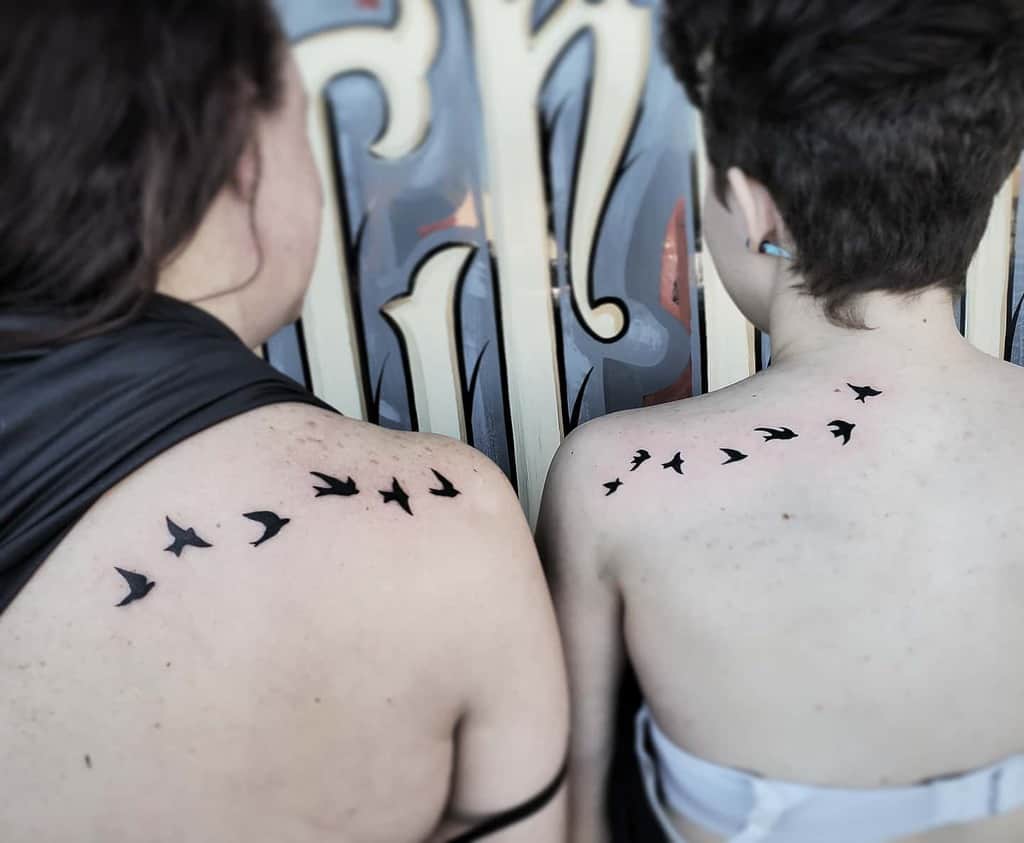 Matching mother-daughter tattoos of silhouette of birds in flight
