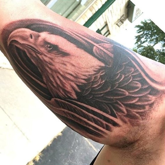 Tattoo of an eagle's head and wings on a person's upper arm