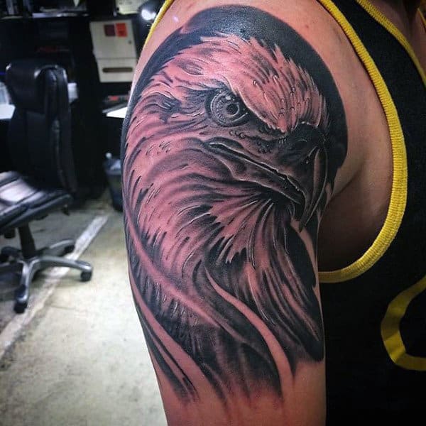 Realistic eagle tattoo on a person's upper arm detailed in black and gray shading