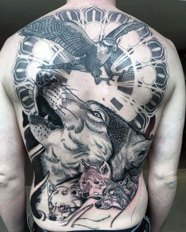 Back tattoo with a howling wolf, three smaller wolves, a hawk, and circular geometric designs