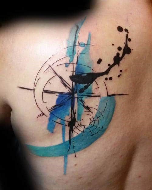 Watercolor compass tattoo with black ink splatter and blue brushstrokes on a shoulder