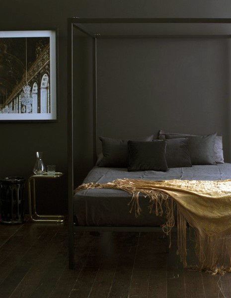 Elegant black bedroom with a canopy bed, gold accents, and a modern framed wall art.