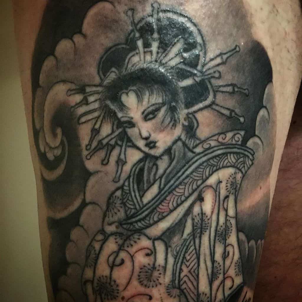 Black and gray tattoo of a Geisha with intricate kimono patterns, a traditional headdress, and swirling clouds in the background.