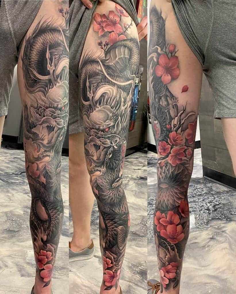 Detailed dragon and cherry blossom leg tattoos in black and red