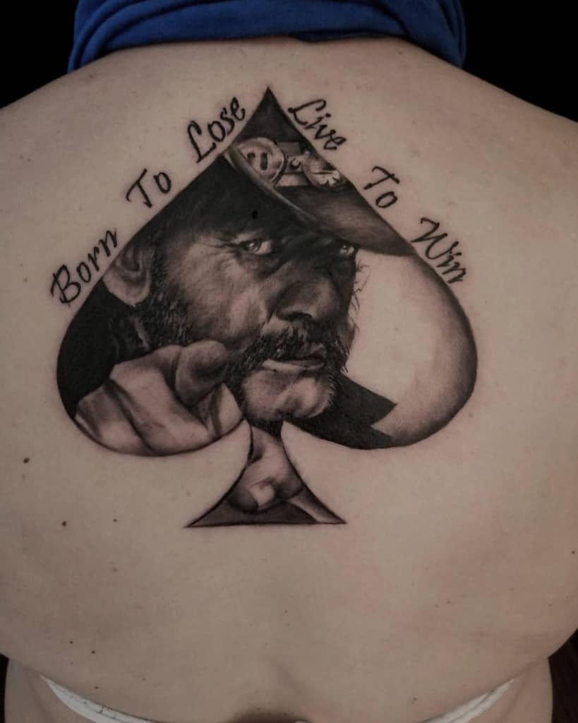 A black-and-white tattoo of a detailed portrait of a man inside an Ace of Spades card, with the text "Born to Lose, Live to Win" above