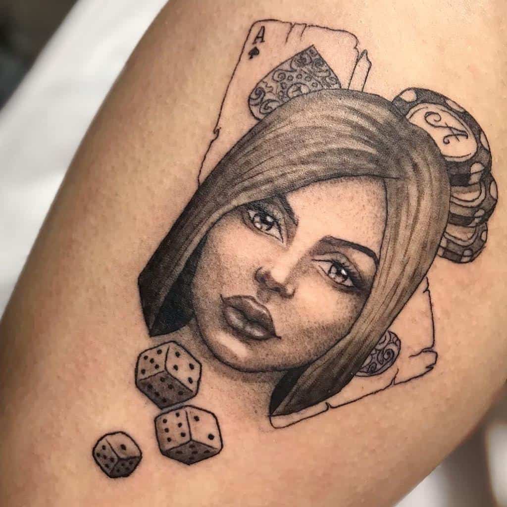 A black-and-white tattoo featuring a woman's portrait, surrounded by an Ace of Spades card, dice, and poker chips