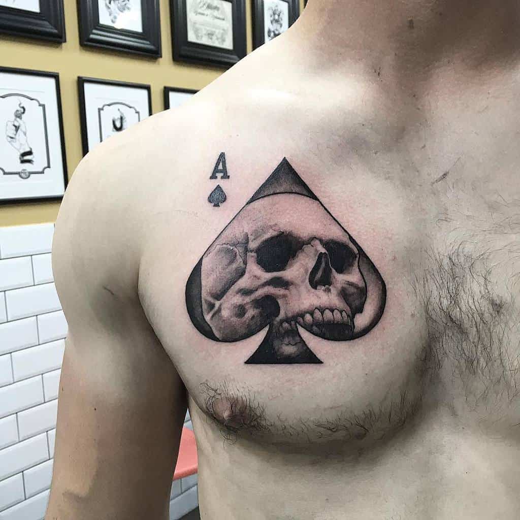 A black-and-white tattoo of the Ace of Spades symbol with a skull integrated into the spade design
