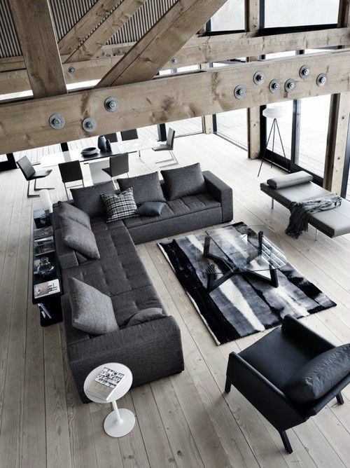 Grey sectional daybed couch in a modern open-plan living room with wooden beams and black accents.