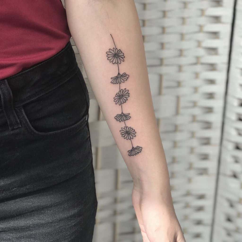 Forearm tattoo fine line work black and grey daisy chain