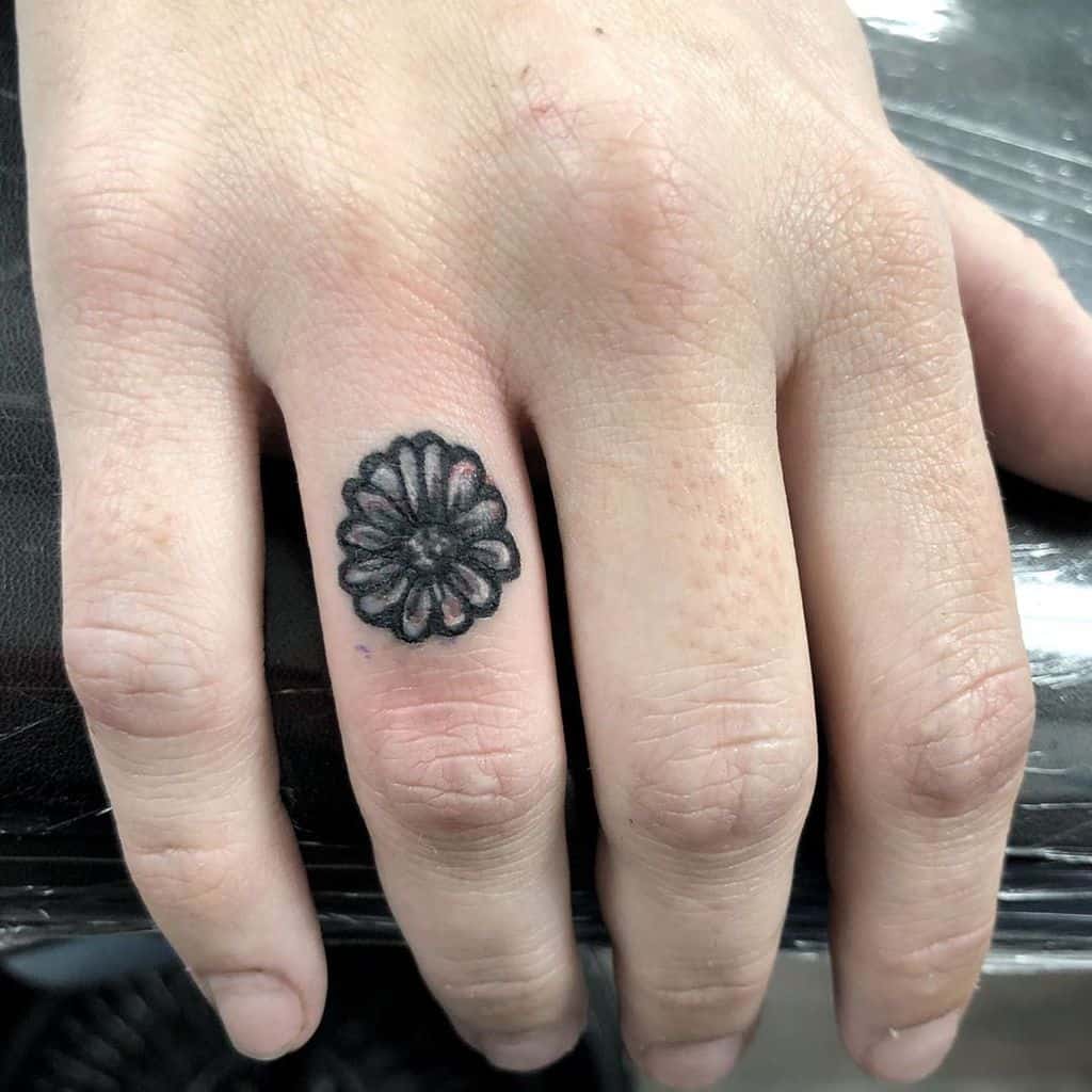 Ring finger tiny black and grey daisy tattoo